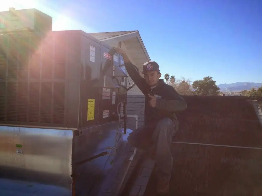 HVAC technician performing AC Tune-Up on a rooftop unit in Cottage Grove